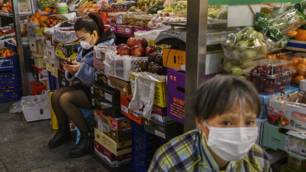 Fruit vendors wear protective masks as they wait for customers at a local market in Beijing, China. 