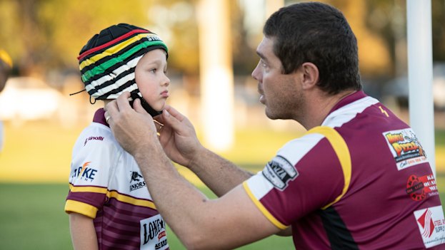 Father Sean Buchanan adjusts the headgear on his six-year-old son Beau, who plays for the Glenmore Park Brumbies in the Penrith Junior Rugby League.