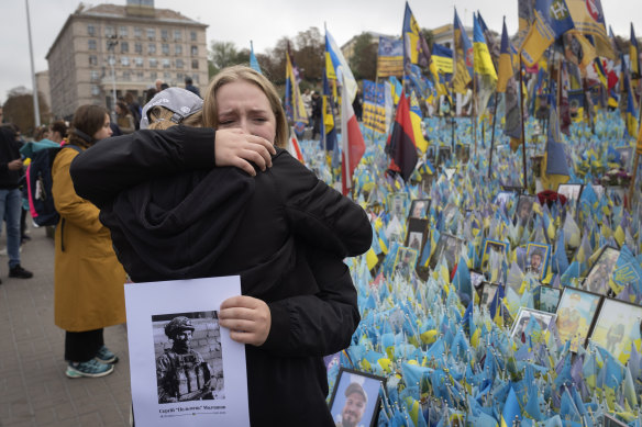 People react during a nationwide minute of silence honouring fallen Ukraine soldiers on Defenders Day at the improvised war memorial in Independence square in Kyiv, on Tuesday.