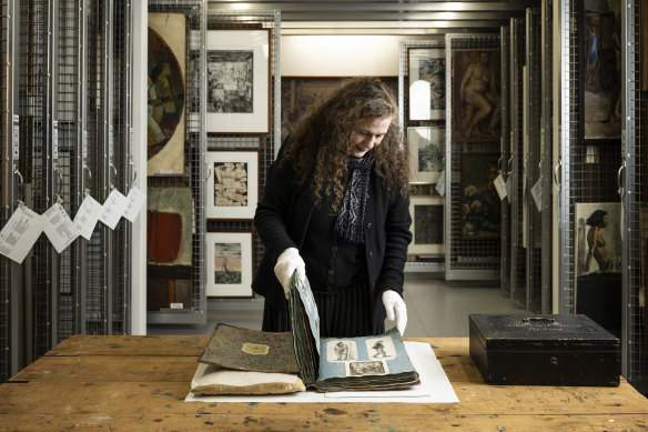 Archivist Deborah Beck examines the scrapbook at the National Art School.