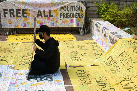 A supporter of pro-democracy activists holds a sign outside West Kowloon Magistrates’ Courts where others queue up for a court hearing over charges  of subversion on Monday.