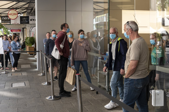 Customers wait outside the Perth Apple Store wearing masks.