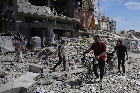 Palestinians walk through rubble along a road beside a clinic destroyed by Israeli airstrikes in Jabalia, in the northern Gaza Strip.