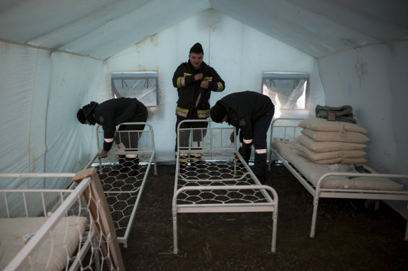 Servicemen set up beds at a tent camp for refugees arriving in Palalanca, Moldova.