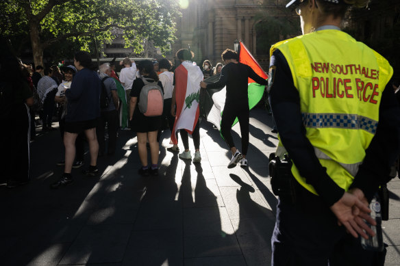 Pro-Palestinian protesters march in Sydney on Monday evening, as police watch on.