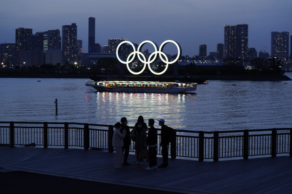 People watch illuminated Olympic rings floating in the waters off Odaiba island in Tokyo.
