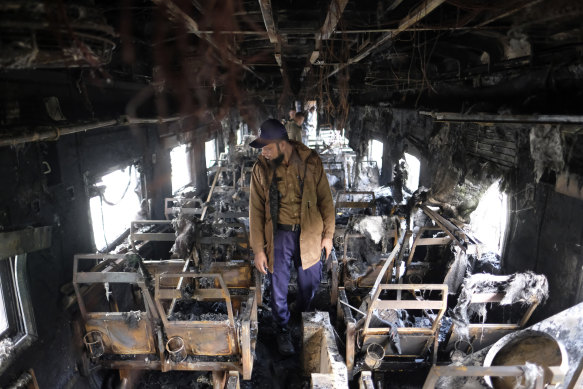 A security officer inspects the damage inside a passenger train that caught fire, killing four people in Dhaka, Bangladesh.