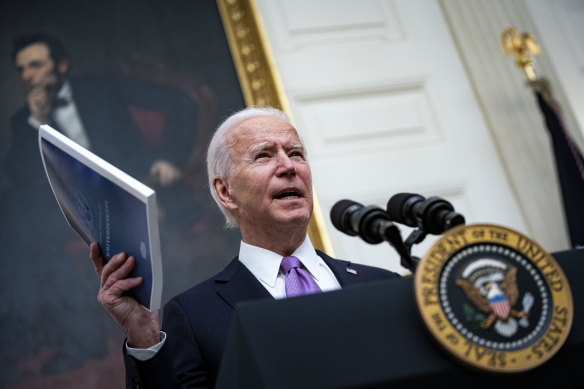 US President Joe Biden holds a copy of his administration's National COVID-19 Strategy booklet as he speaks about his efforts to address the pandemic in the US.