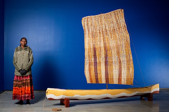 Helen Ganalmirriwuy Garrawurra with dugout canoe and woven pandanus sail.