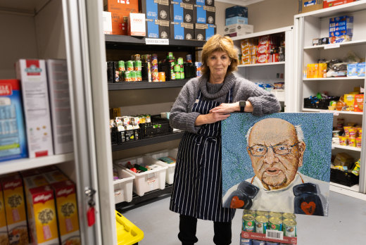 Volunteer Anne Moloney in the pantry with a portrait of Father Bob Maguire.
