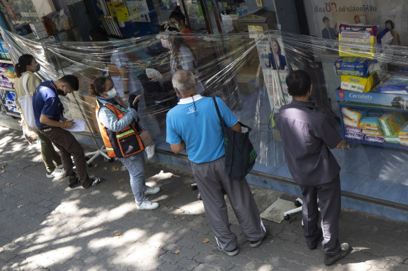 Customers order medicines through a protective plastic sheet at a pharmacy in Bangkok on Thursday.
