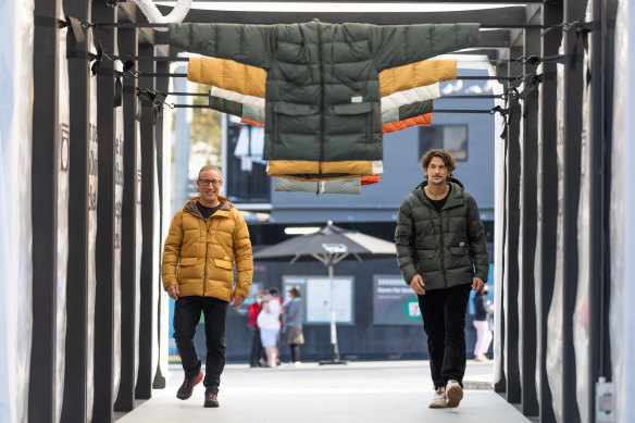 Kathmandu chief executive Reuben Casey with Jarrod Scott, wearing the BioDown biodegradable puffer jacker in a pop-up installation by Joost Baker made using clothing destined for landfill.
