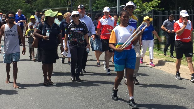 Student Ikanau Conway carries the Queen's Baton on Palm Island on Wednesday.