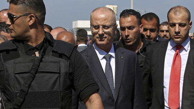 PM Rami Hamdallah (center), surrounded by bodyguards, arrives for the opening of a sewage plant project.