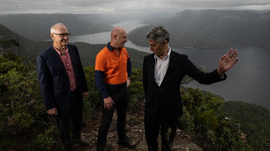 Ross and Anthony Garnaut, director and chief executive of Zen Energy, stand on either side of the WaterNSW chief Andrew George at the site of the proposed Western Sydney pumped hydro project.
