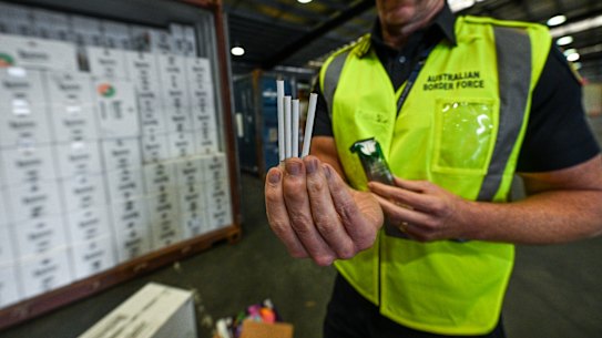 A Border Force officer inspects illegal cigarettes in a shipping container.