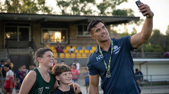 Joseph-Aukuso Suaalii poses with two young players at Nepean Rugby Park in Penrith.