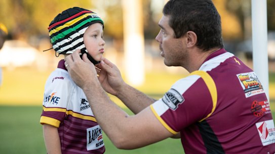 Sean Buchanan adjusts the headgear on his son Beau, who plays for the Glenmore Park Brumbies in the Penrith Junior Rugby League.