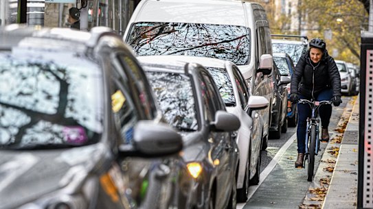 Cyclists make their way along a narrow bike lane along Collins Street.