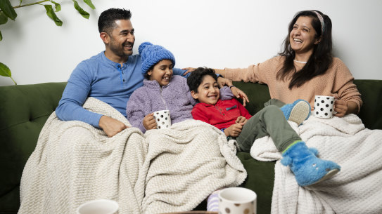 Anshul Wadhwa and Aradhita Nadkarni with their children, Aanya, 10, and Asher, 7, keep warm in their Randwick flat with hot drinks, blankets and warm clothes.