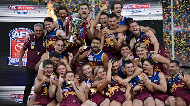 Brisbane Lions teammates celebrate with the premiership cup.
