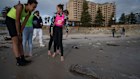 Beachgoers inspect a dead Snapper on Glenelg Beach