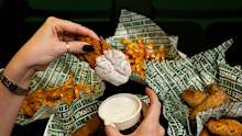 A Wingstop chicken wing being dipped into sauce