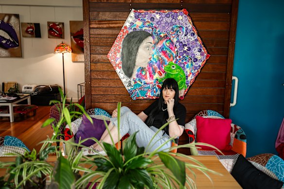 Justine Martin lives with MS, pictured in front of a self-portrait, portraying her life story through illness, disability, resilience and moving forward despite the obdtacles in her way.