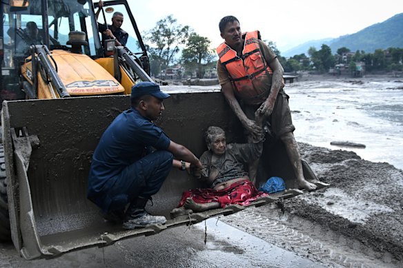 Rescuers use an excavator to help move a flood survivor to safety in Devghat, in the Nepal’s Nuwakot district, on August 26.