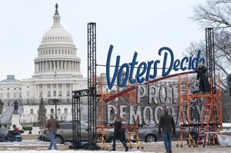 A year after the attack on the US Capitol, people walk past a sign as it is finalised to say, “Voters Decide Protect Democracy last week.