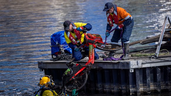 A diver and colleagues removes rubbish from the Yarra on Monday, including an e-bike from Uber’s Jump brand, now owned by Lime.