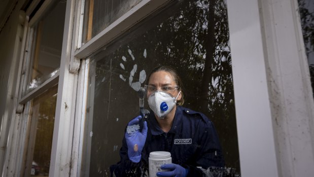 Forensic officer Deborah Hughes dusts a window.