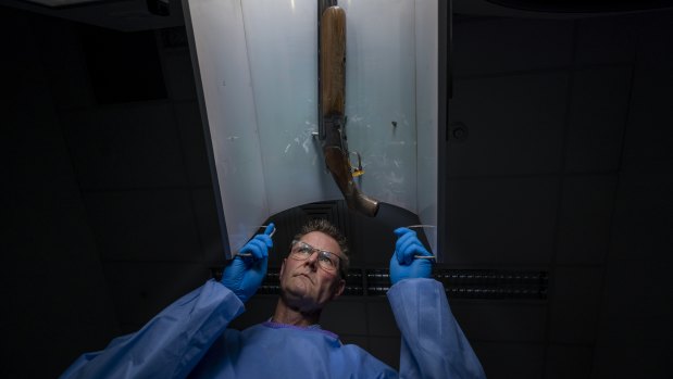 Forensic officer Craig Hewitson sets a gun in place with a series of magnets.