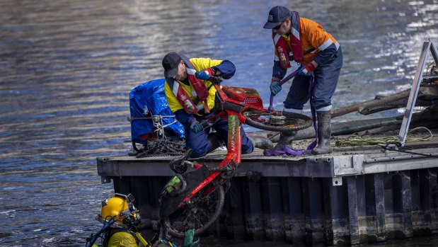 A diver and colleagues removes rubbish from the Yarra on Monday, including an e-bike from Uber’s Jump brand, now owned by Lime.