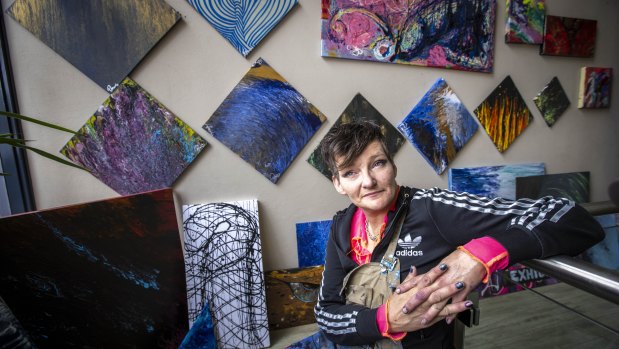 Painter with some of the artworks from her exhibition From Adversity to Creativity.