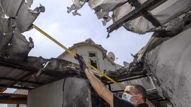 An Israeli police officer inspects damage to a home Israel said was hit by a rocket fired by Palestinian militants from the Gaza Strip.