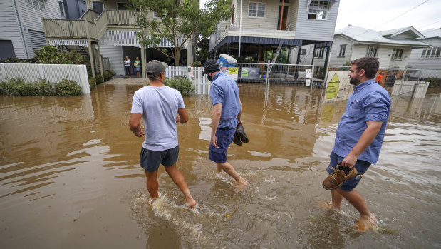 People walk to their homes in a flooded Vincent Street, Auchenflower, in Brisbane.