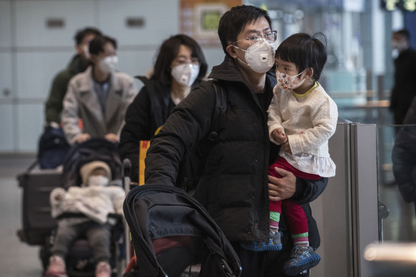 Passengers wear protective masks as they walk in the arrivals area at Beijing Capital Airport.