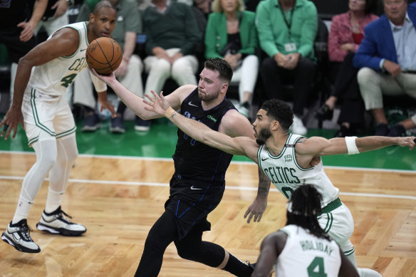Dallas Mavericks guard Luka Doncic, drives with the ball as Boston Celtics center Al Horford, left, and forward Jayson Tatum, right.
