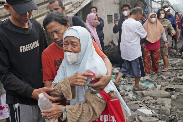 A woman weeps as she is lead away from the site of the fire on Saturday.