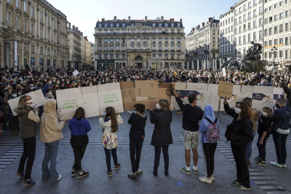 People hold a large banner that reads: 'Don't touch my teacher', in front of the crowd in Lyon, central France, on Sunday.