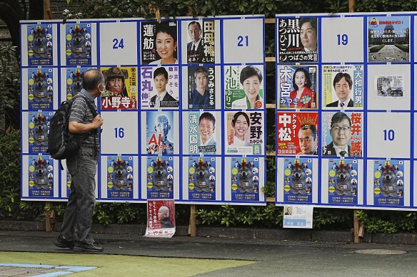 A person looks at an election poster board for Tokyo gubernatorial election.