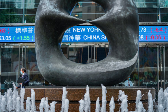 A sculpture stands in front of a stock ticker at the Exchange Square complex, which houses the Hong Kong Stock Exchange. The struggle to maintain confidence in Hong Kong's future is manifesting in its stock and currency markets. 