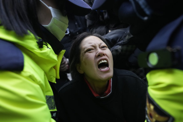 Police officers escort away a supporter of the president.