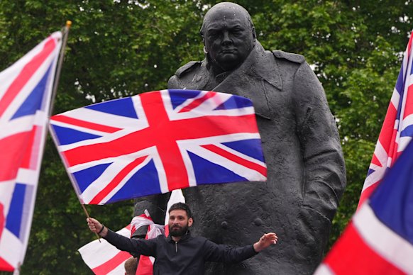 Manifestantes agitam bandeiras na estátua de Winston Churchill, em Londres.