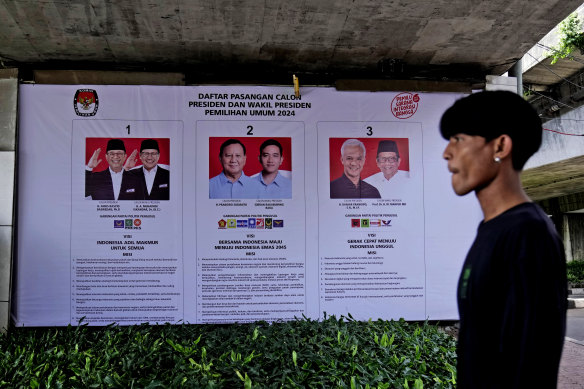 A man walks past a General Election Commission’s banner showing the presidential candidates, from left, Anies Baswedan and his running mate Muhaimin Iskandar, Prabowo Subianto and his running mate Gibran Rakabuming Raka, and Ganjar Pranowo and his running mate Mahfud MD in Jakarta.