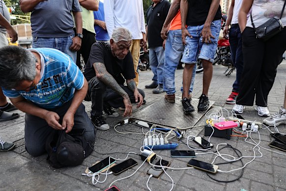 People charge phones and batteries after explosions and low-flying aircraft were heard in the early hours in Caracas.