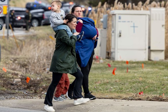 Famílias são escoltadas para fora do local do ataque na Sinagoga Temple Israel, no estado americano de Michigan.
