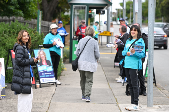 Party volunteers hand out how-to-vote cards at the early voting centre in Camberwell. 