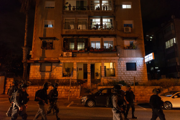 Residents watch from their balconies a moment before police to deal with a  fire lit by rioters at the scene in Haifa, Israel